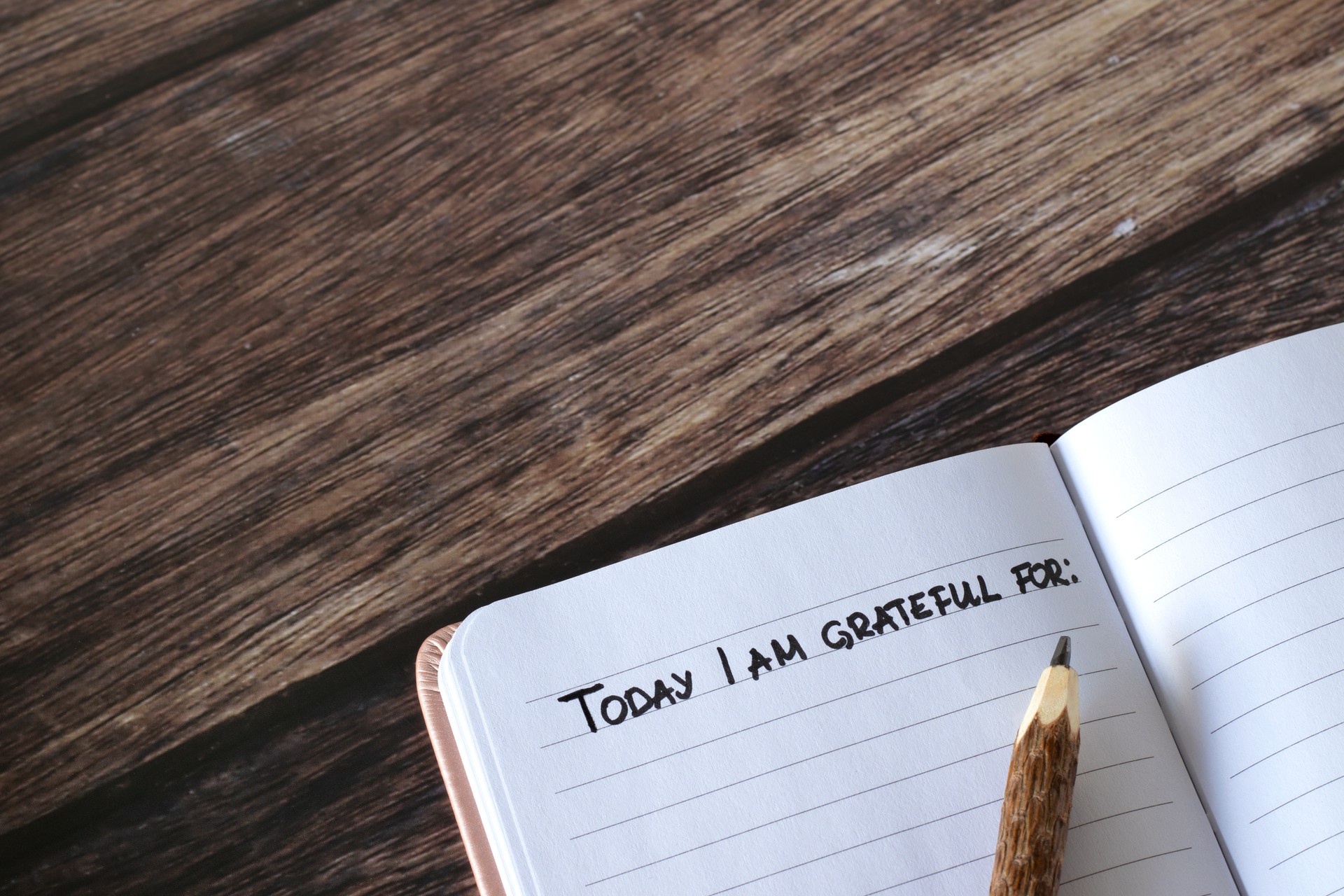 Open journal with handwritten text for gratitude and thanksgiving and pencil on wooden table, top view, copy space